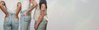 Three people wearing light blue jeans and gemstone bracelets against a white background