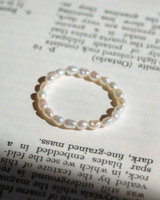 White pearl ring on top of book page.