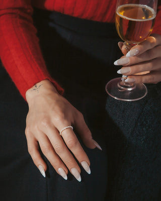 Person holding a glass of champagne with a close-up of a hand wearing a ring.