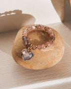 A stretch ring with a coffee moonstone centerpiece and a dangling heart charm