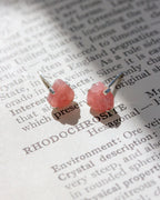 Pink Rhodochrosite post earrings on a book page with text.