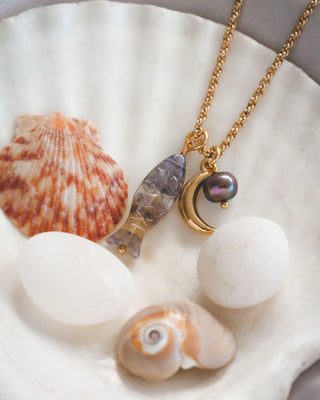 Necklace with a fish and moon design on a shell background