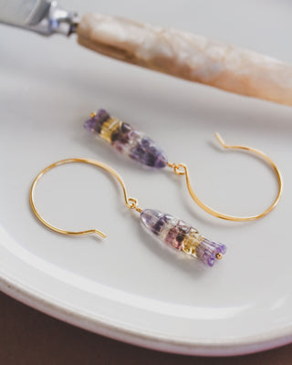 Gold hoop earrings with colorful fluorite on a white plate