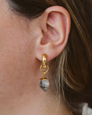 Closeup of woman wearing a herkimer quartz gold hoop earring.