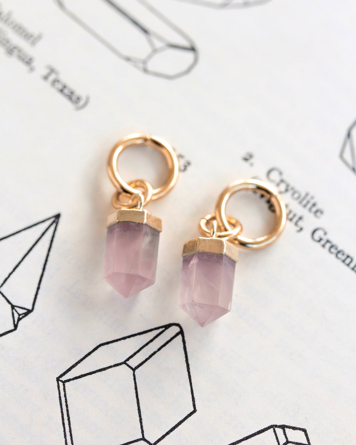 Interchangeable hoop earring charms with pink rose quartz pendants attached to gold hoops