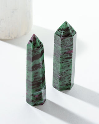 Two polishedruby zoisite gemstone towers with a green and ruby-red marbled appearance, placed on a white surface.