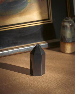 Black crystal tower on a textured surface with a framed picture in the background