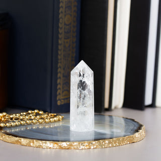 Clear crystal tower on a dark surface with books in the background