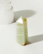 Banded Calcite Obelisk crystal with neutral and green tones.