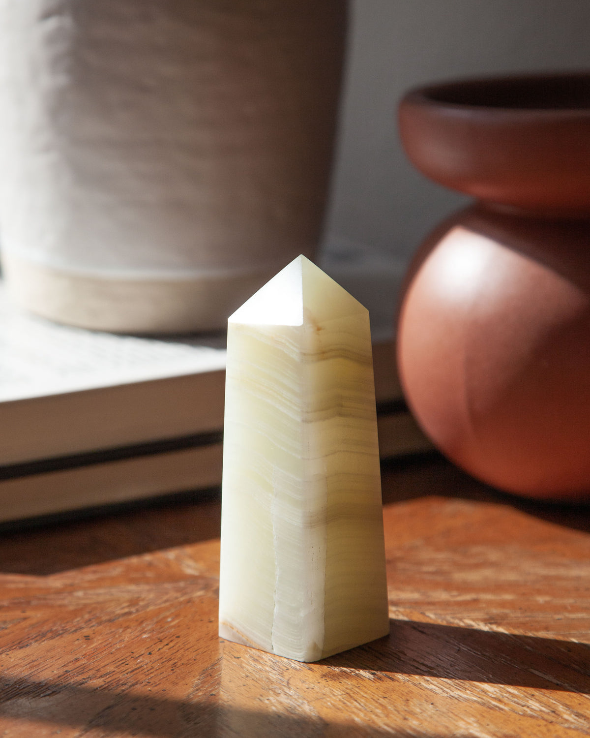 Obelisk Calcite Crystal with subtle bands of white on a wooden table.