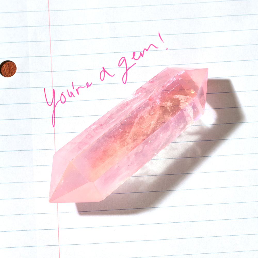 Rose Quartz wand on lined paper with pink handwriting 'You're a gem!'.