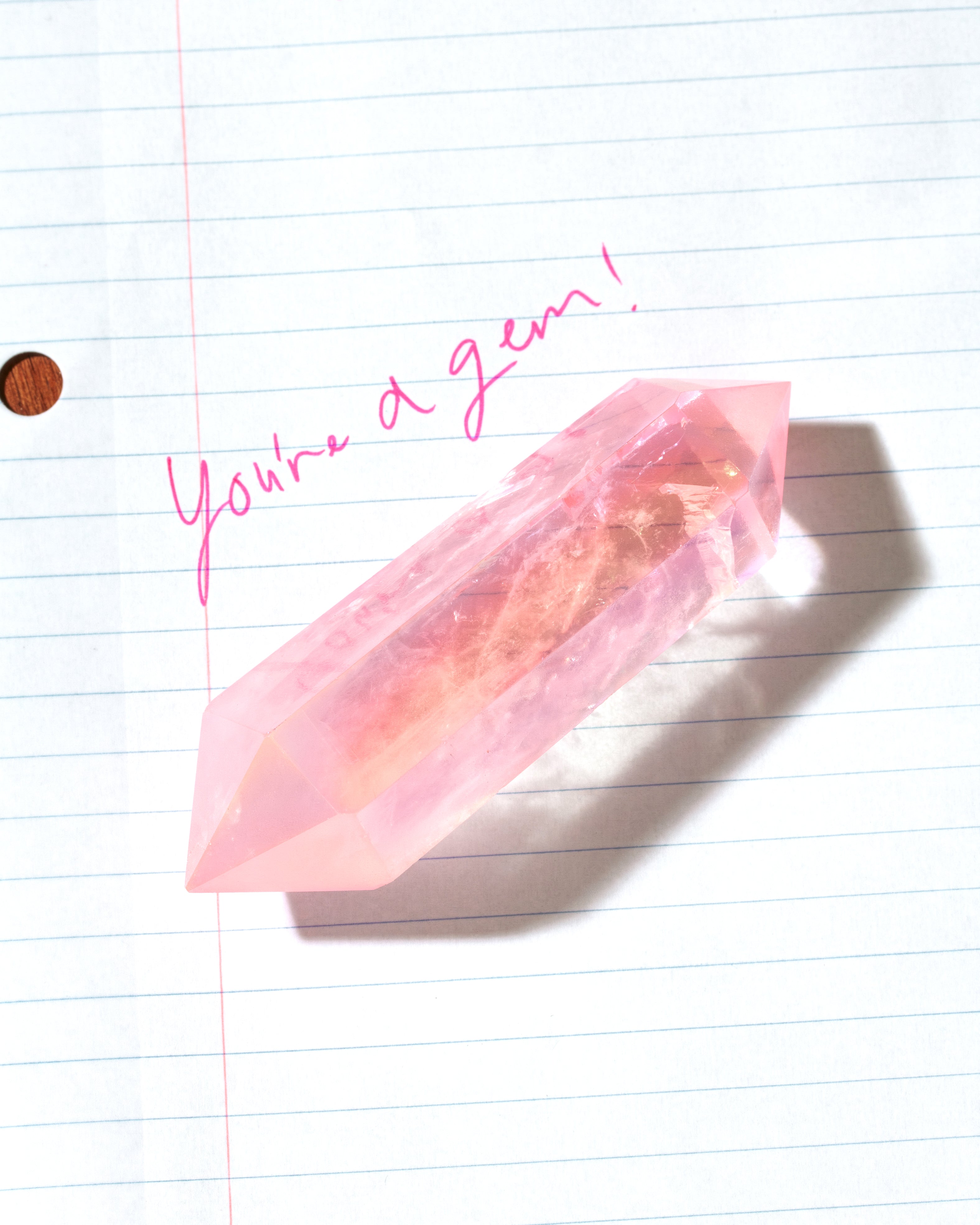 Rose Quartz wand on lined paper with pink handwriting 'You're a gem!'.