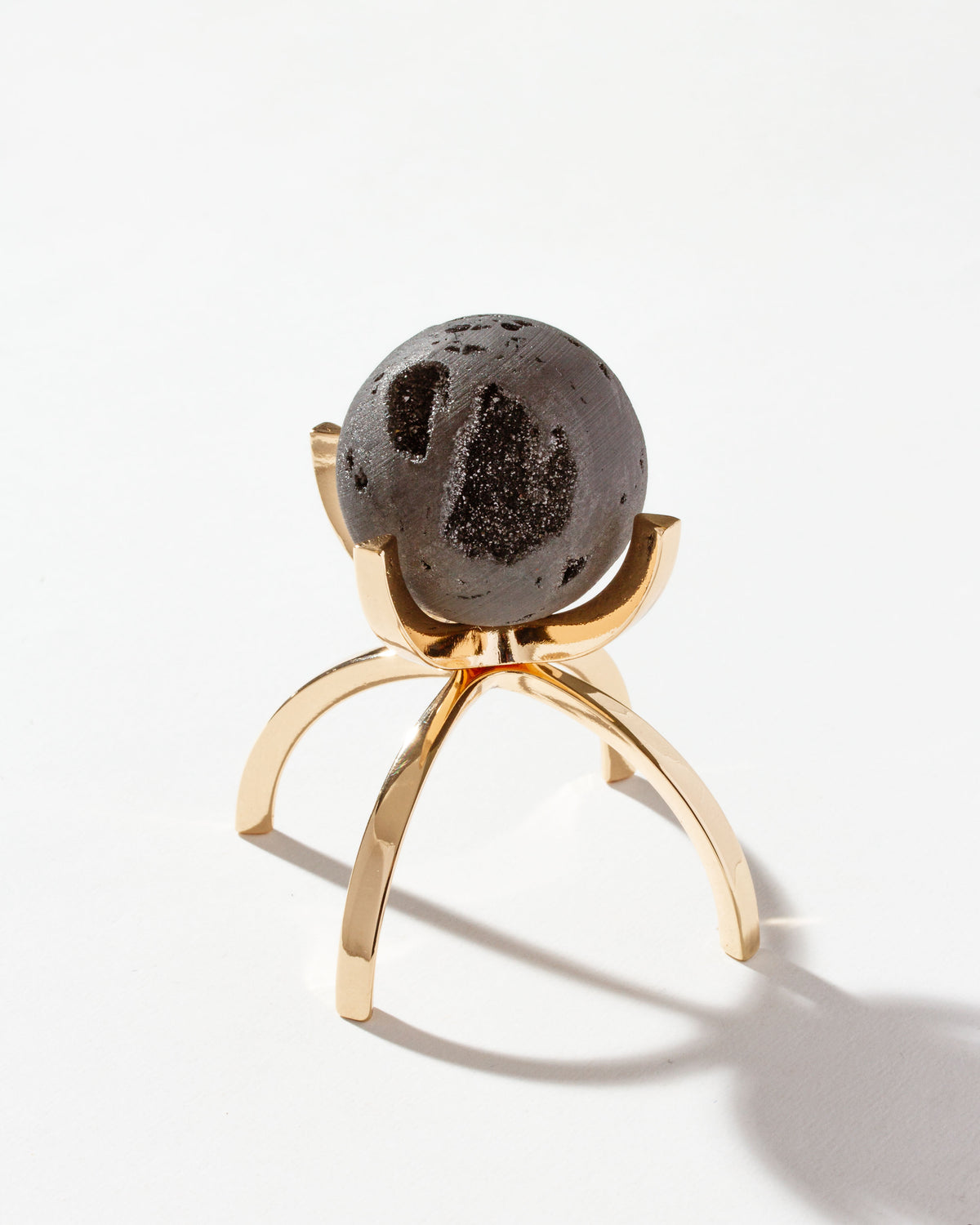 Black druzy gemstone sphere on a gold stand.