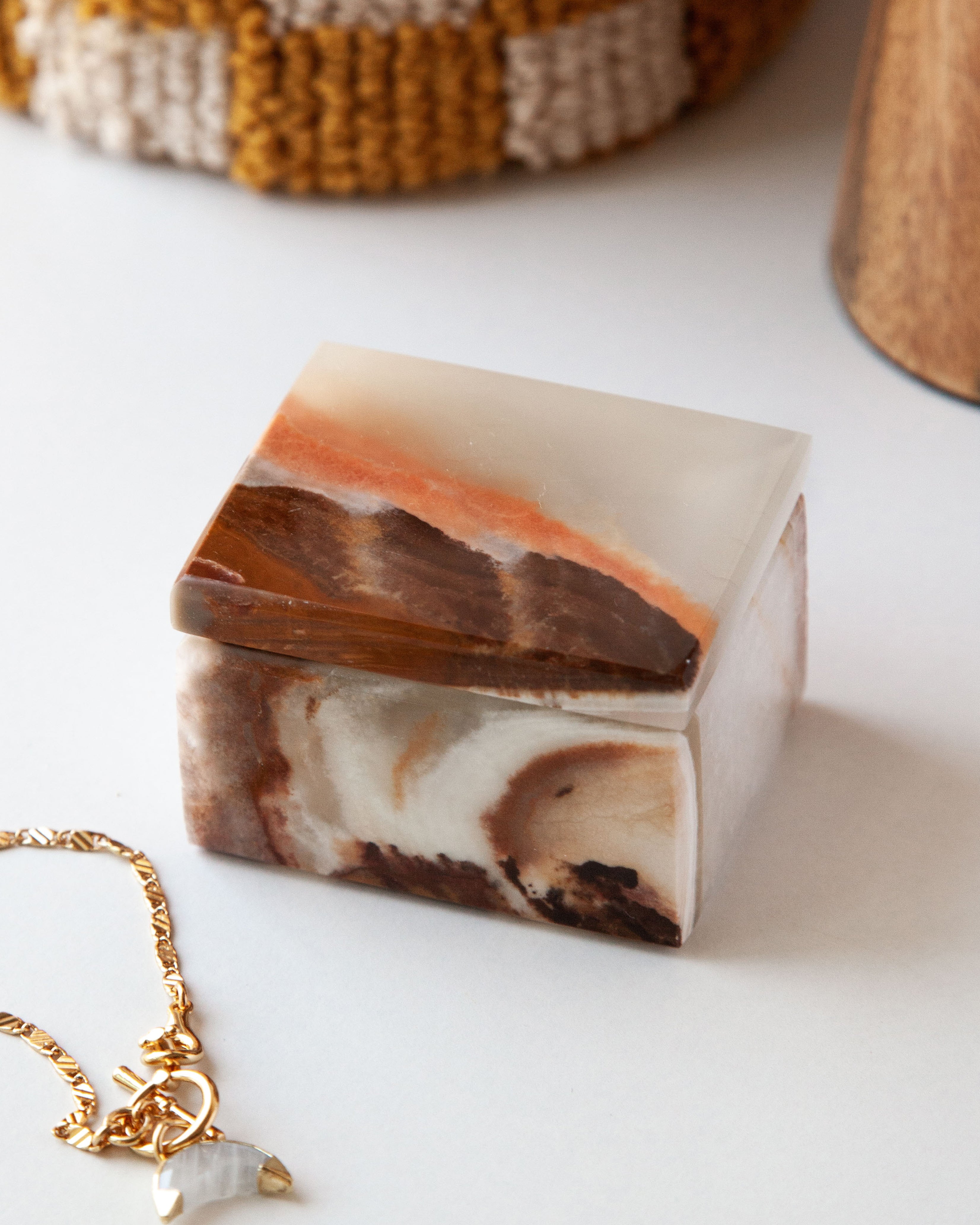 Brown and white Calmly Organized Calcite Jewelry Box on a white surface with a gold chain.