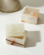 Two calcite jewelry boxes, one brown-striped and open, the other closed.