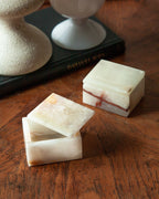 White Calcite jewelry boxes with lids on a wooden surface.