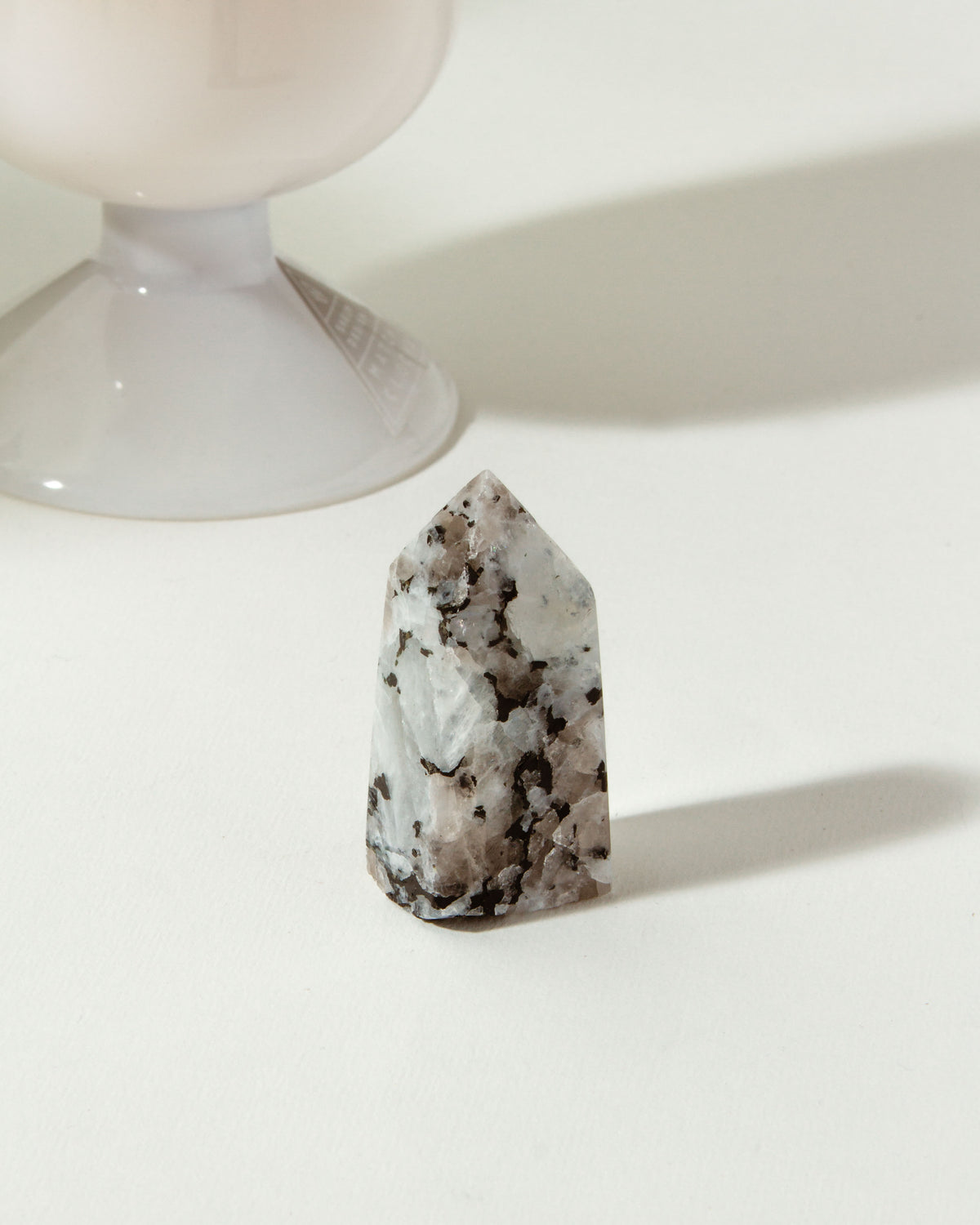 Lovestrong Moonstone Obelisk Tower with white and black speckles, displayed near a white vase.