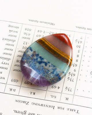 Colorful worry stone teardrop Chakra gemstone on a book.