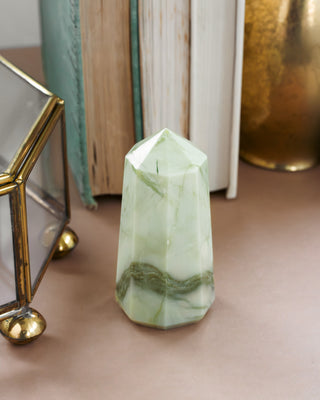 Green crystal on a surface with books and decorative items in the background
