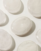 Many smooth quartz stone with a slight indent, placed on a white surface.