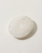 Smooth quartz stone with a slight indent, placed on a white surface.