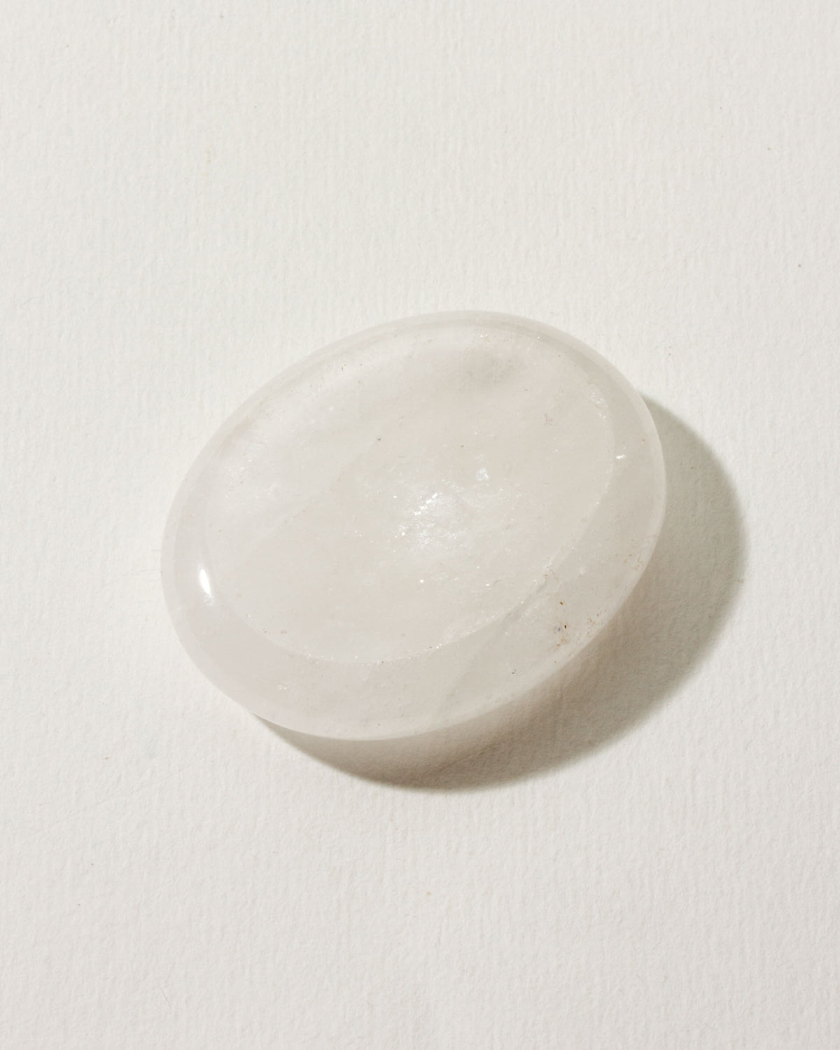 Smooth quartz stone with a slight indent, placed on a white surface.