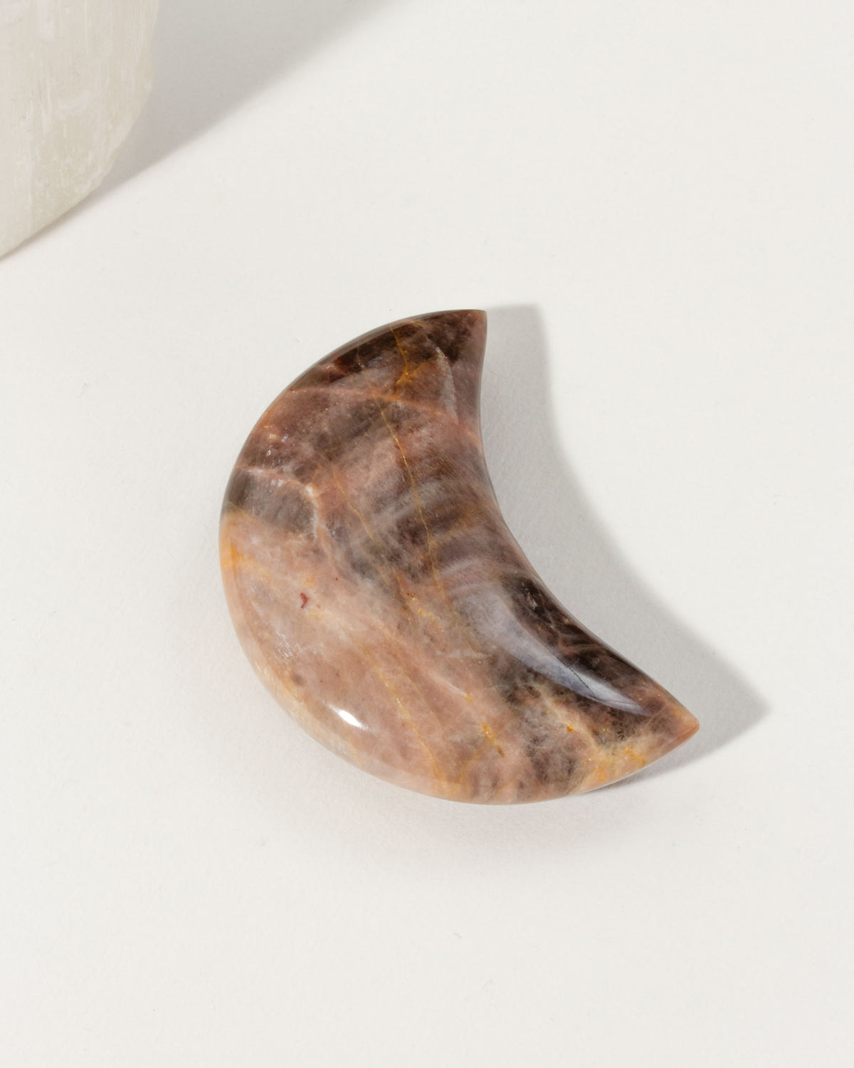 Waxing crescent moon-shaped brown moonstone gemstone with a polished surface.