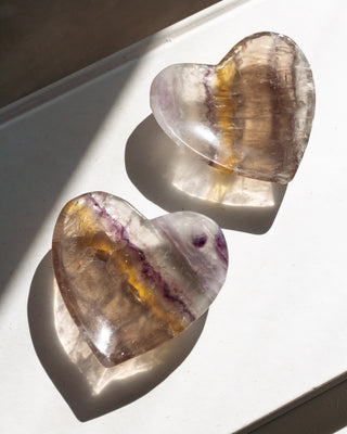 Two heart-shaped Rainbow Fluorite bowls on a white surface
