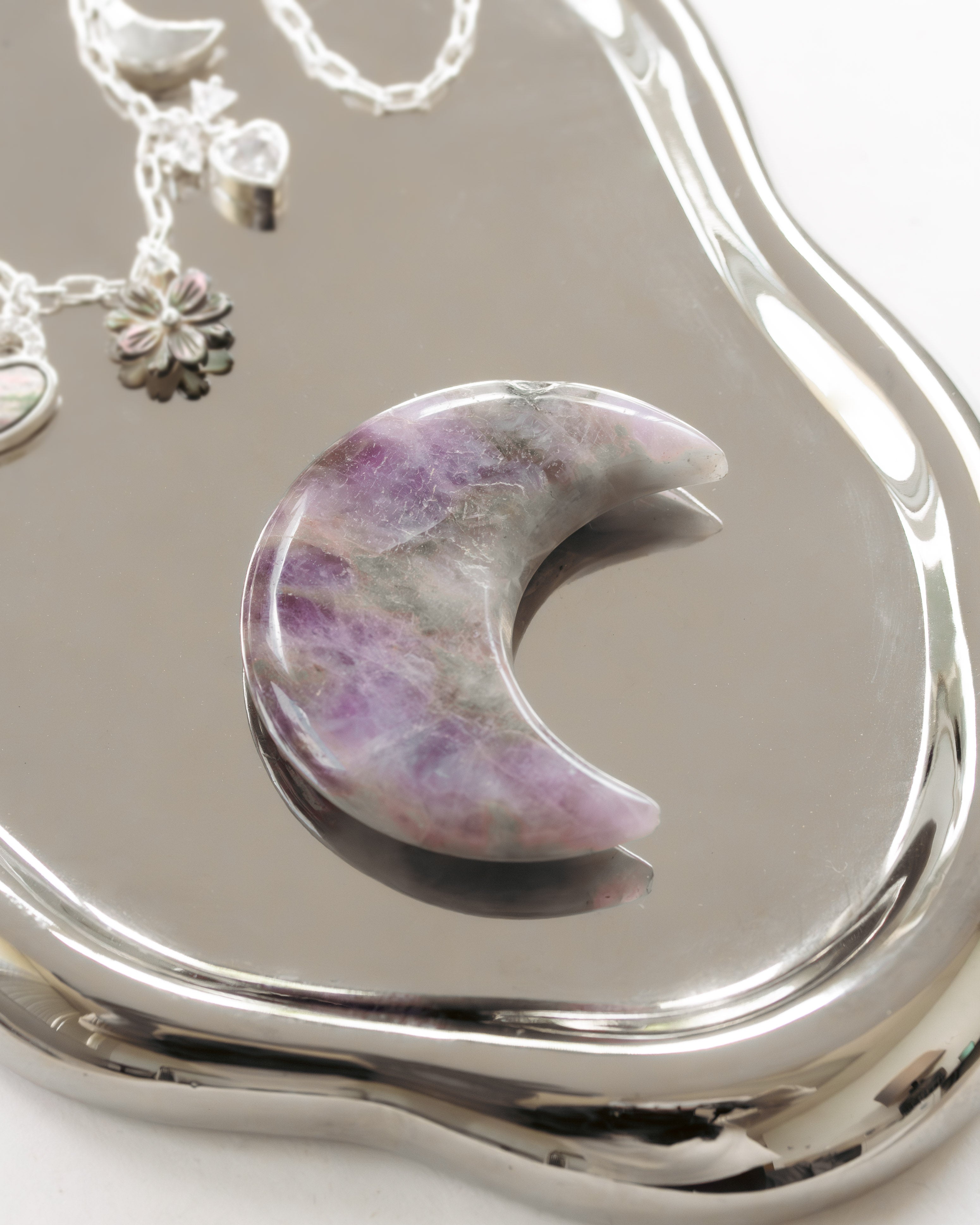 Purple amethyst crescent moon curio laying on a mirror