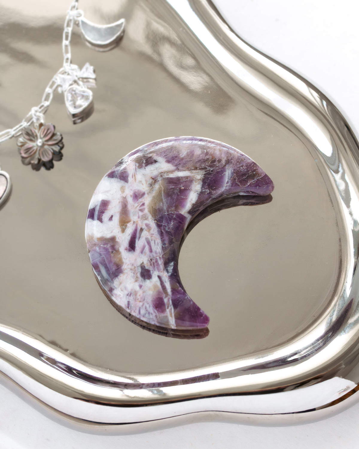 Purple amethyst crescent moon stone on a silver mirror, detailing surface patterns