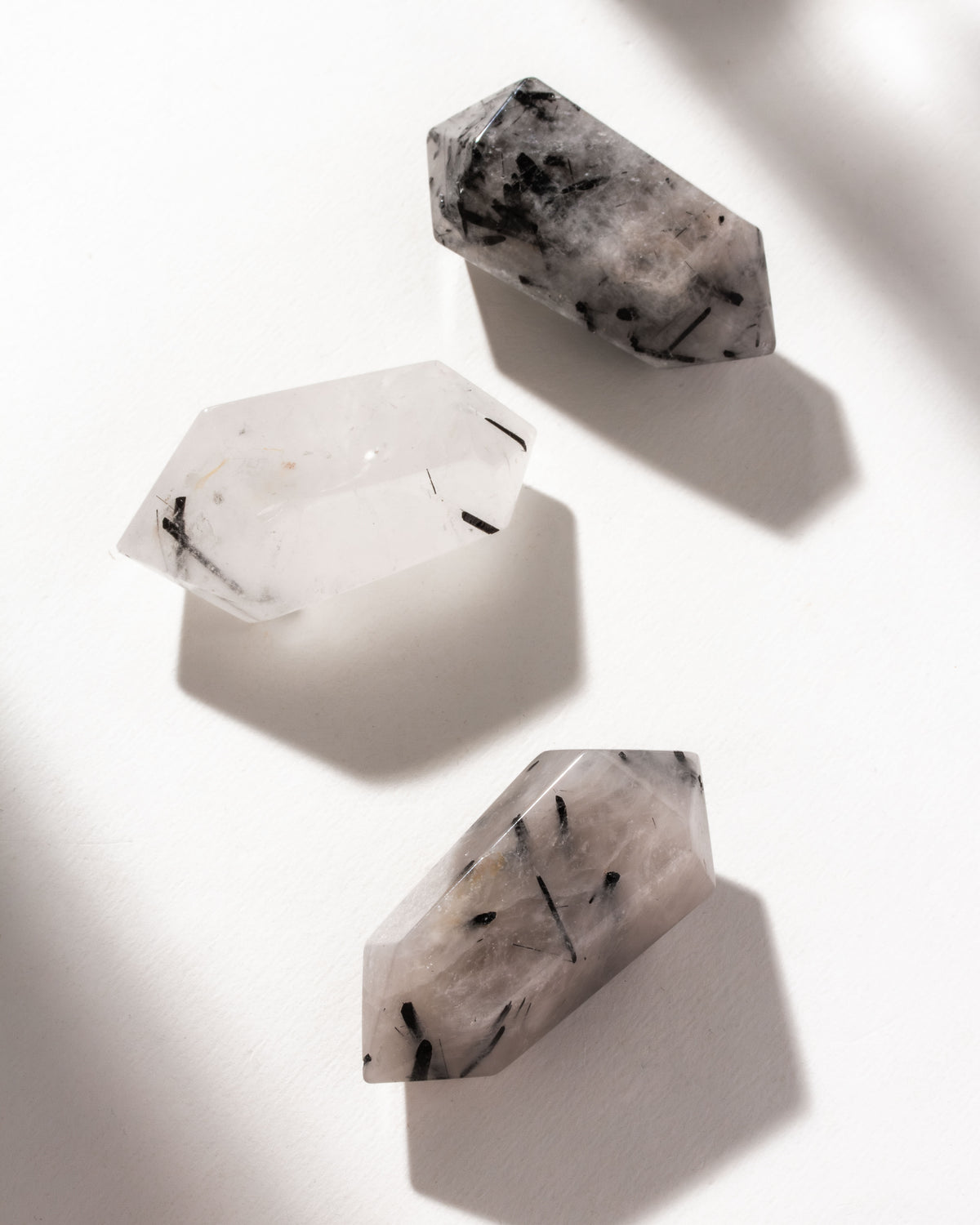 Three tourmalinated quartz crystals, with clear and black inclusions, are