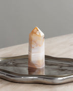 Banded striped stone crystal on a metallic surface with a neutral background