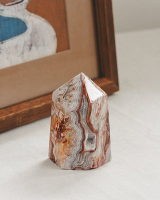 Polished agate stone on a white surface with a blurred framed picture in the background