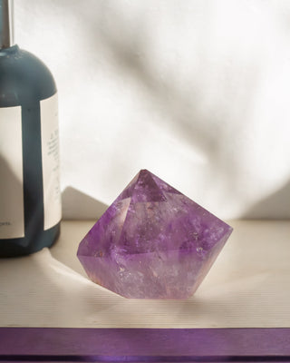 Amethyst crystal on a white surface with a blurred background