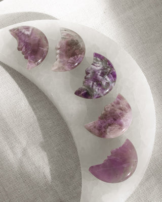 Decorative amethyst moon face carved item with purple amethyst stone on a white base