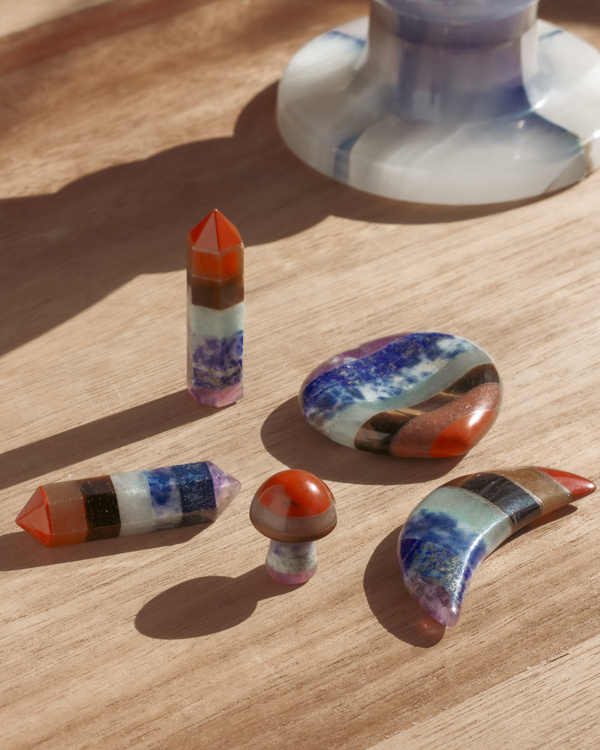 Arrangement of five colorful multilayered gemstone curios on a wooden surface