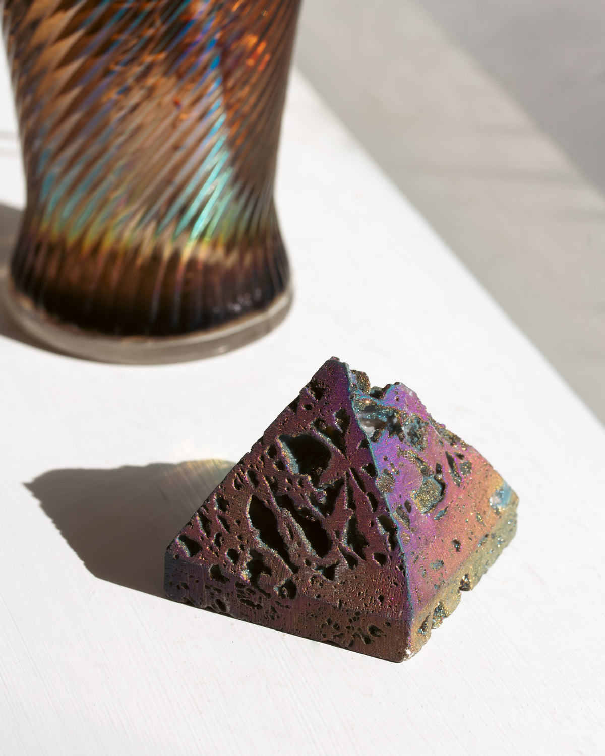 Colorful textured rainbow fnish druzy stone on a white surface with a blurred background