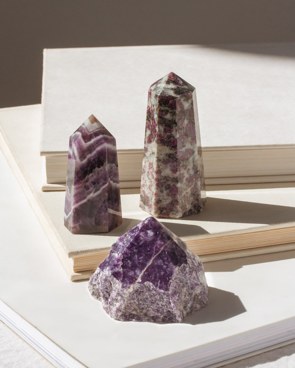Set of 3 genuine stone crystal towers in shades of purple displayed on a book.