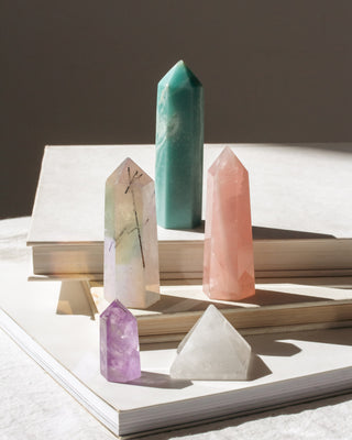 Variety of gemstone towers stacked on books including amethyst and quartz