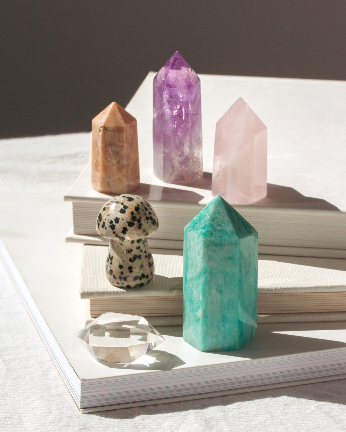 Variety of gemstone towers with Ocean Jasper mushroom curio, stacked on top of books