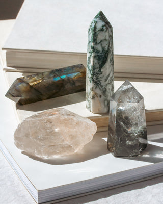 Set of 4 genuine stone crystals in shades of clear and green displayed on a book.