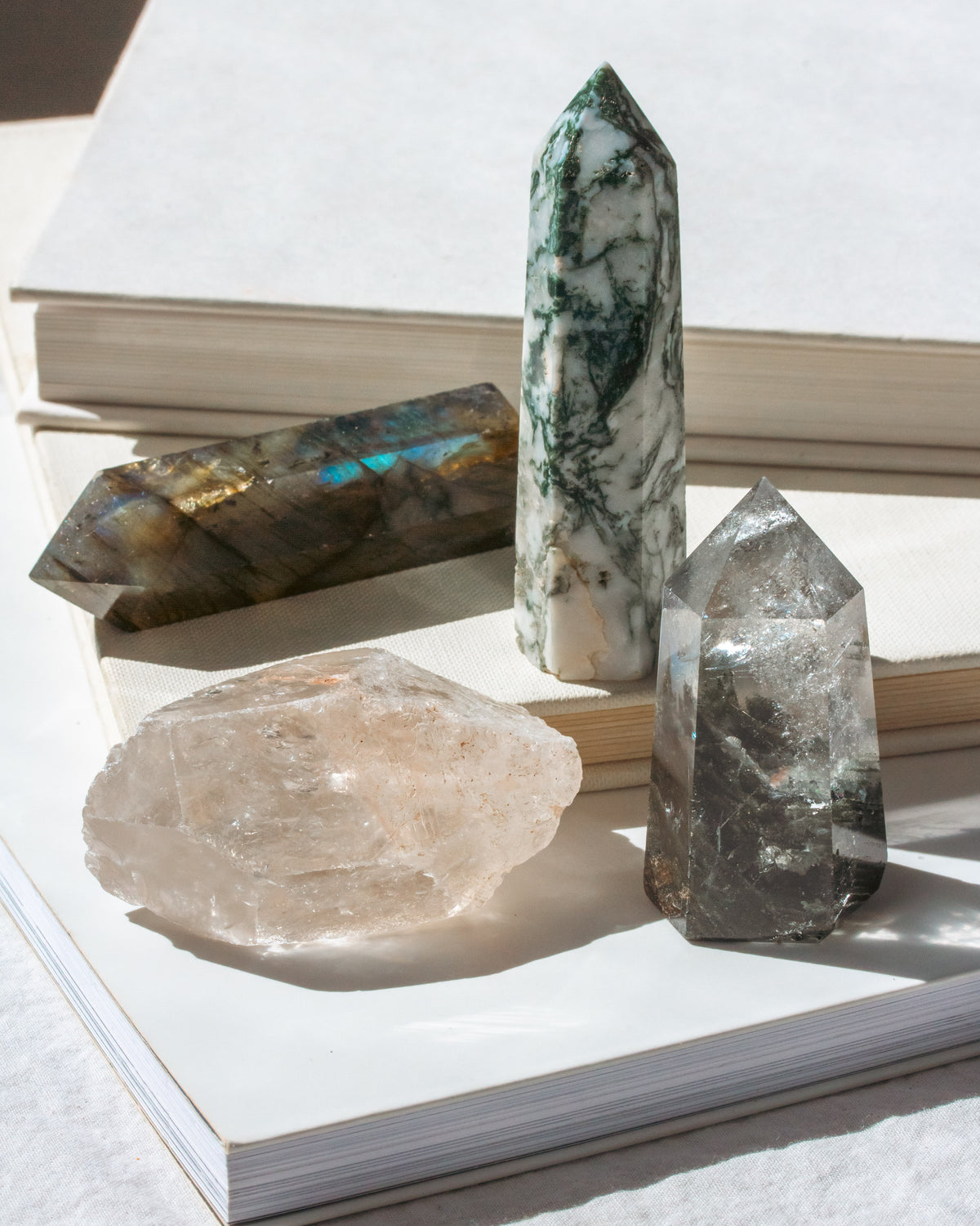 Set of 4 genuine stone crystals in shades of clear and green displayed on a book.