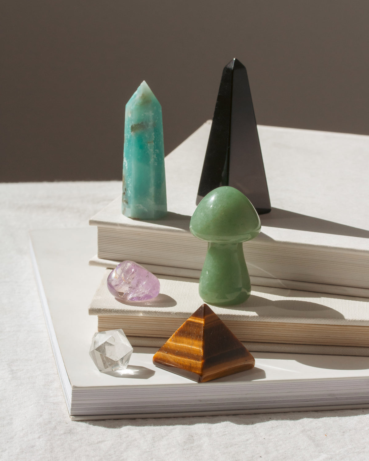 Various gemstone crystals and shapes on books with Tiger's eye pyramid and onyx obelisk.