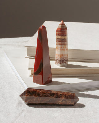 Set of 3 curio gemstone crystals in shades of red displayed on a book.