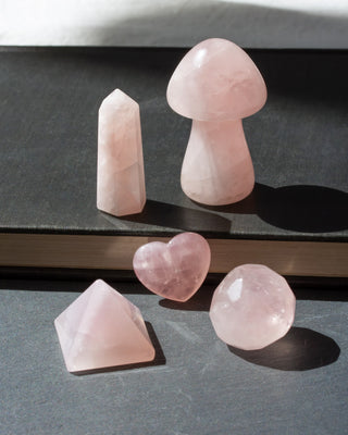 The Love Story Gemstone Set features 5 genuine rose quartz curios in a playful assortment of shapes that celebrate the beauty of variety.

This curated collection includes a heart, pyramid, faceted geometric sphere, carved standing mushroom, and mini tower, each showcasing the soft blush hues and natural charm of genuine rose quartz. From whimsical carvings and polished facets to classic geometric forms, every piece offers a different perspective on this beloved gemstone.