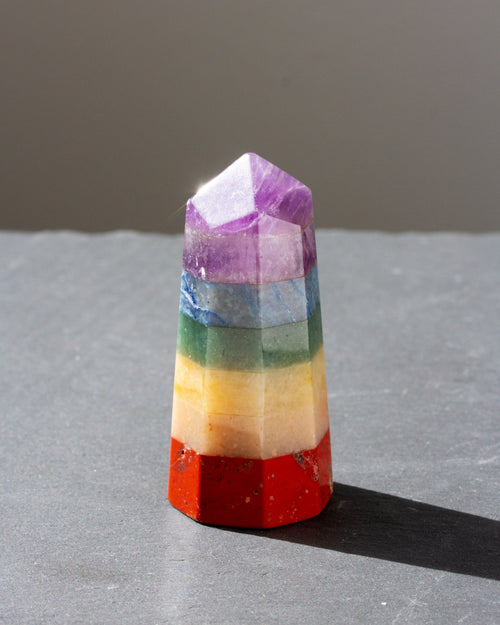 A hexagonal crystal tower featuring stacked rainbow-colored layers of red, orange, yellow, green, blue, and purple.