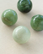Four Serpentine spheres sitting on a textured white surface.