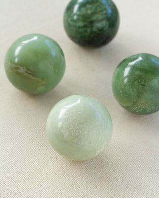 Four Serpentine spheres sitting on a textured white surface.