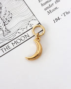 Gold-plated crescent moon hoop earring on a Moon tarot card page
