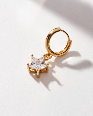 A single gold-colored hoop earring with a sparkling CZ star charm attached to it, displayed against a white background.